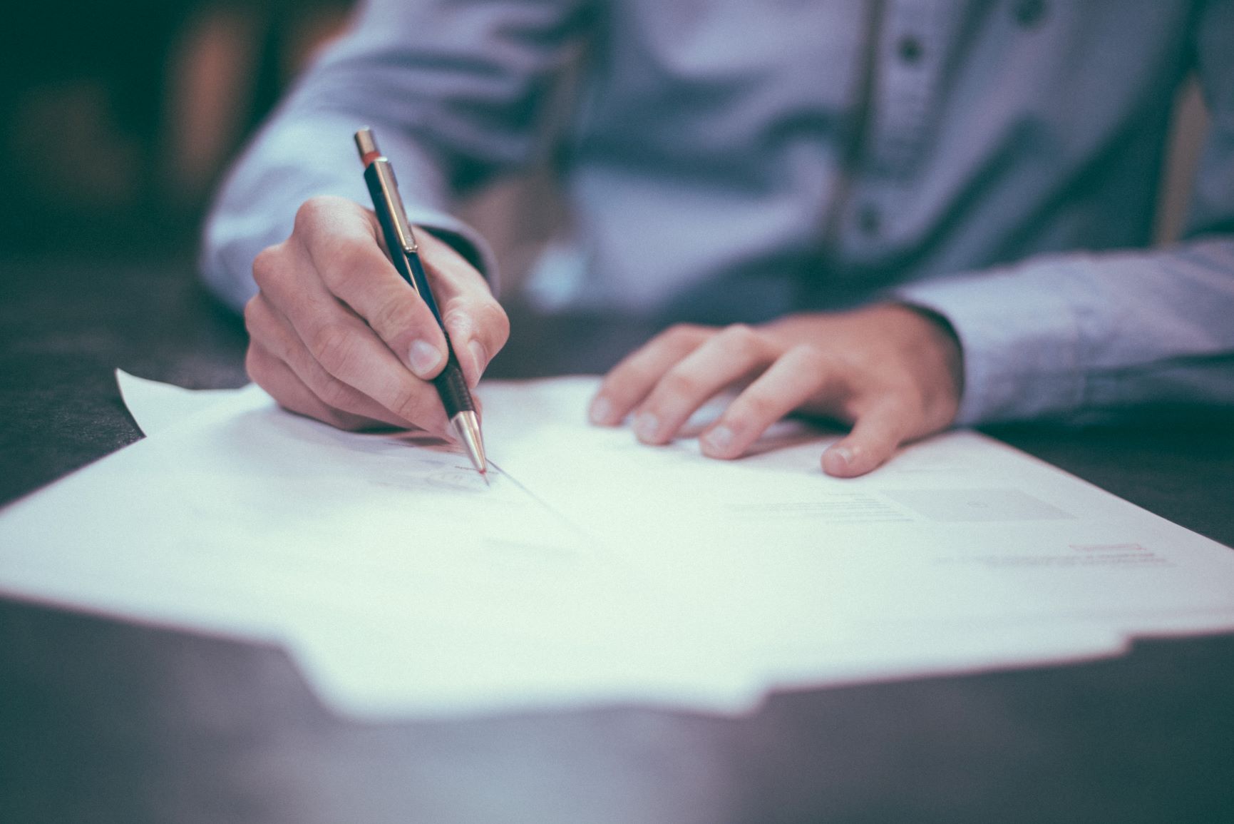 Person filling out forms on desk